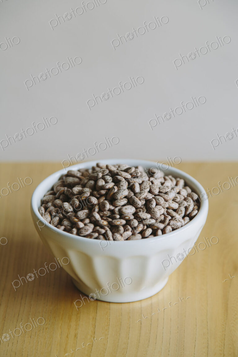 A white round china bowl of kidney beans on a table top.