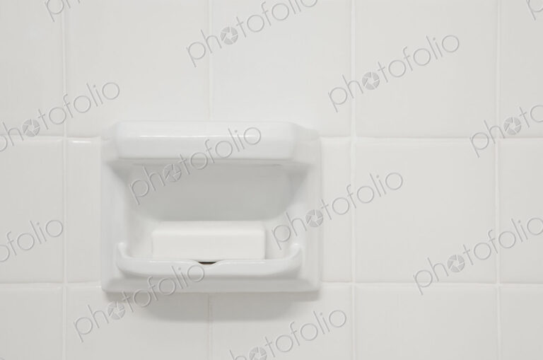 A white tiled wall of a bathroom or shower room,with a shaped porcelain recess. A…