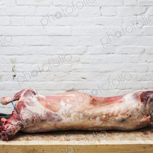 A whole lamb carcass on a butcher's block ready for butchering.