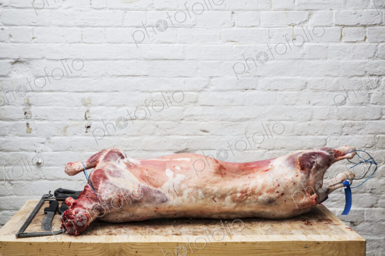 A whole lamb carcass on a butcher's block ready for butchering.