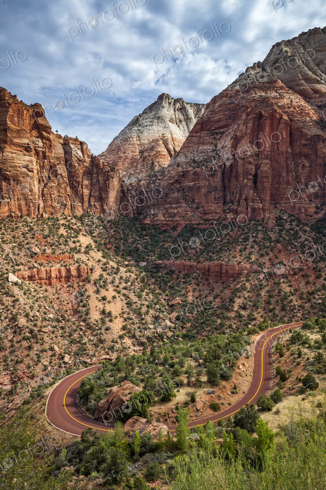 A winding switchback road cuts through the rugged terrain of Zion National Park,…
