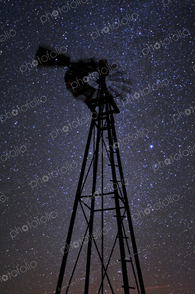 A windmill tower at night, against a starry sky, low angle view.