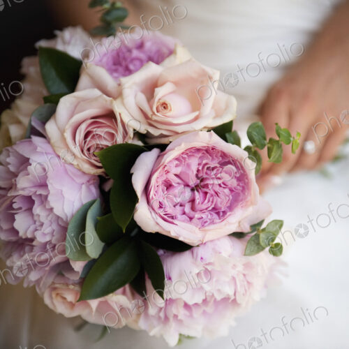 A woman, a bride holding a bridal bouquet of pastel coloured pale pink roses and… A woman, a bride holding a bridal bouquet of pastel coloured pale pink roses and…
