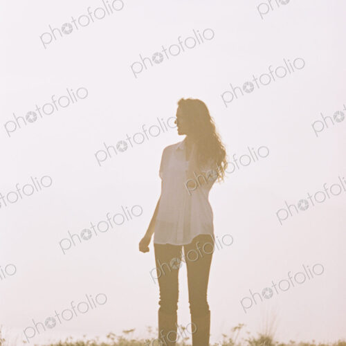 A woman alone standing on a hilltop.