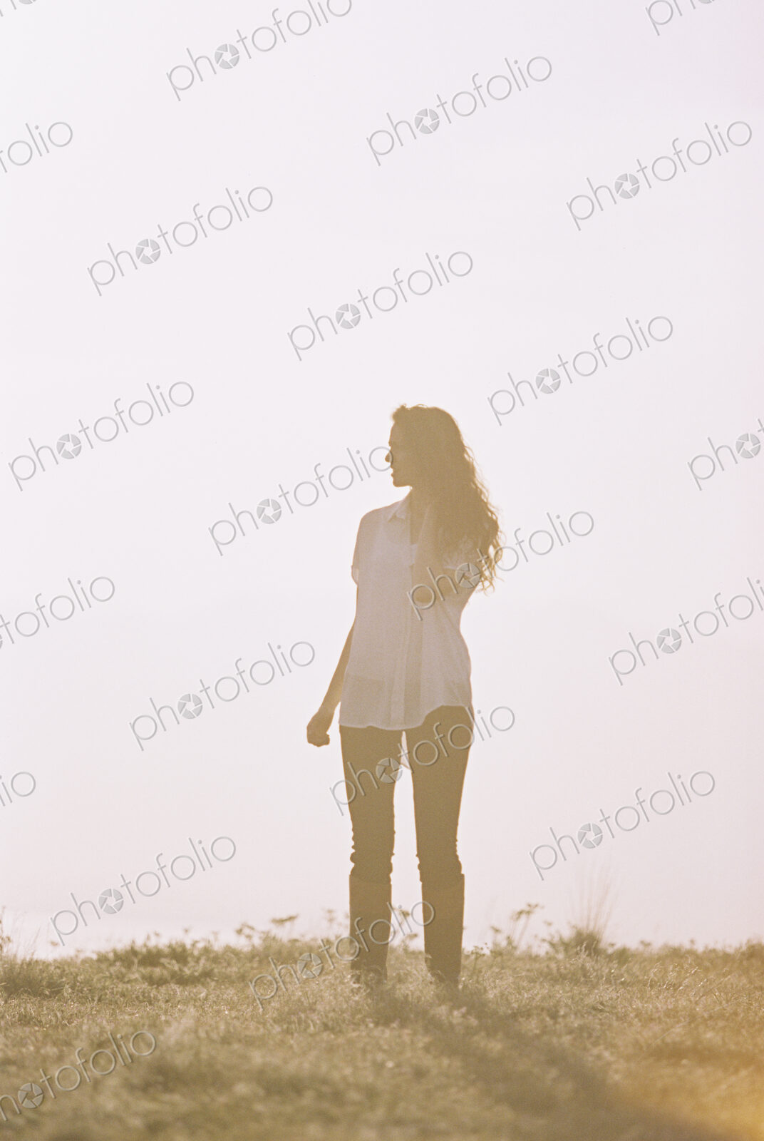 A woman alone standing on a hilltop.