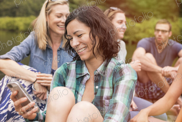 A woman among a group in summer using her smart phone.