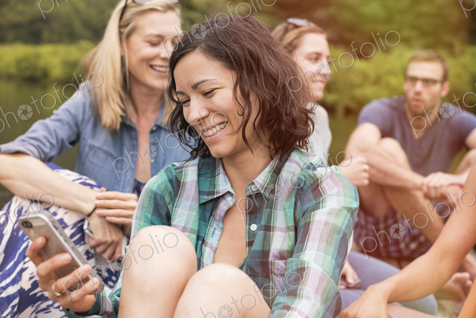 A woman among a group in summer using her smart phone.