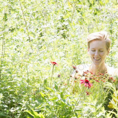 A woman among dense plantings of flowers and tall green and flowering plants
