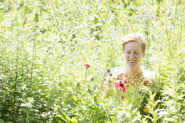 A woman among dense plantings of flowers and tall green and flowering plants