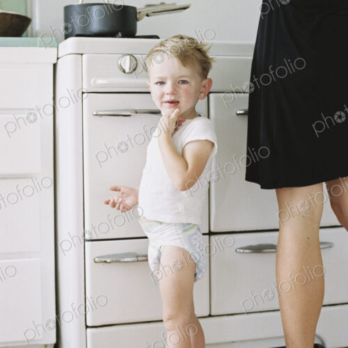 A woman and a child, a young boy standing barefoot in a kitchen. A woman and a child, a young boy standing barefoot in a kitchen.