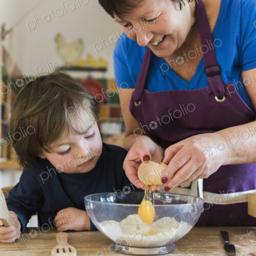 A woman and a child cooking at a kitchen table, making fairy cakes.