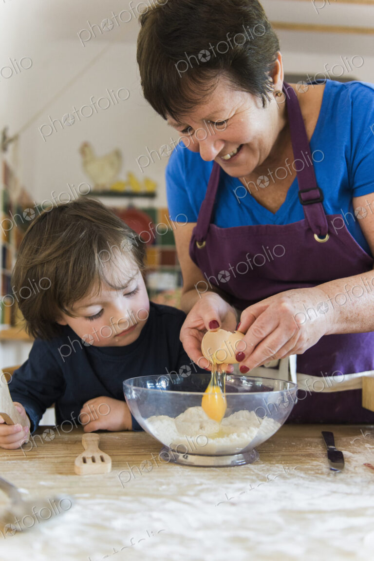 A woman and a child cooking at a kitchen table, making fairy cakes.