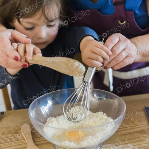A woman and a child cooking at a kitchen table, making fairy cakes.