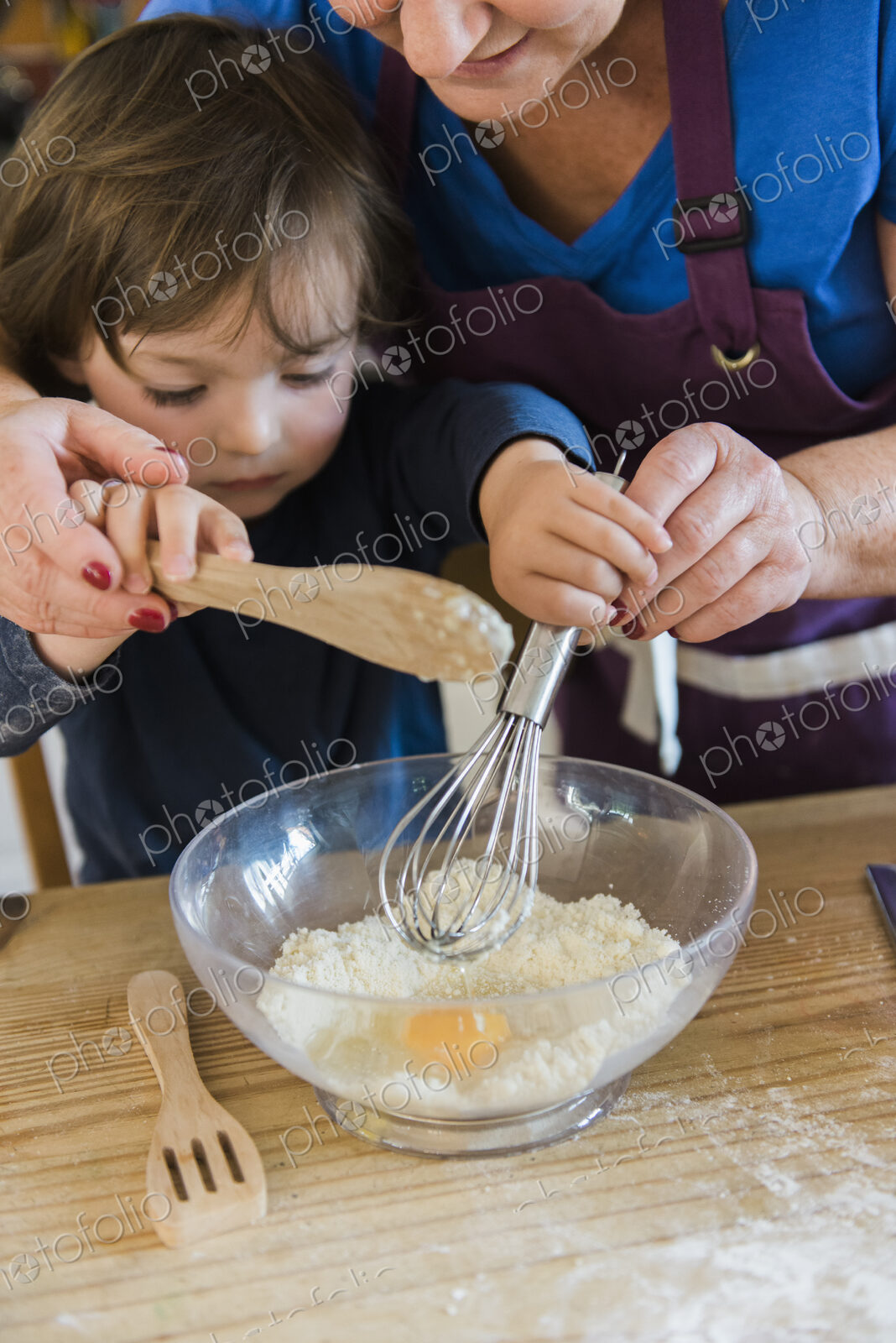 A woman and a child cooking at a kitchen table, making fairy cakes.