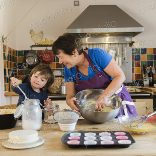 A woman and a child cooking at a kitchen table, making fairy cakes.