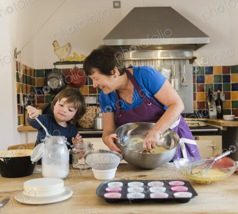 A woman and a child cooking at a kitchen table, making fairy cakes.