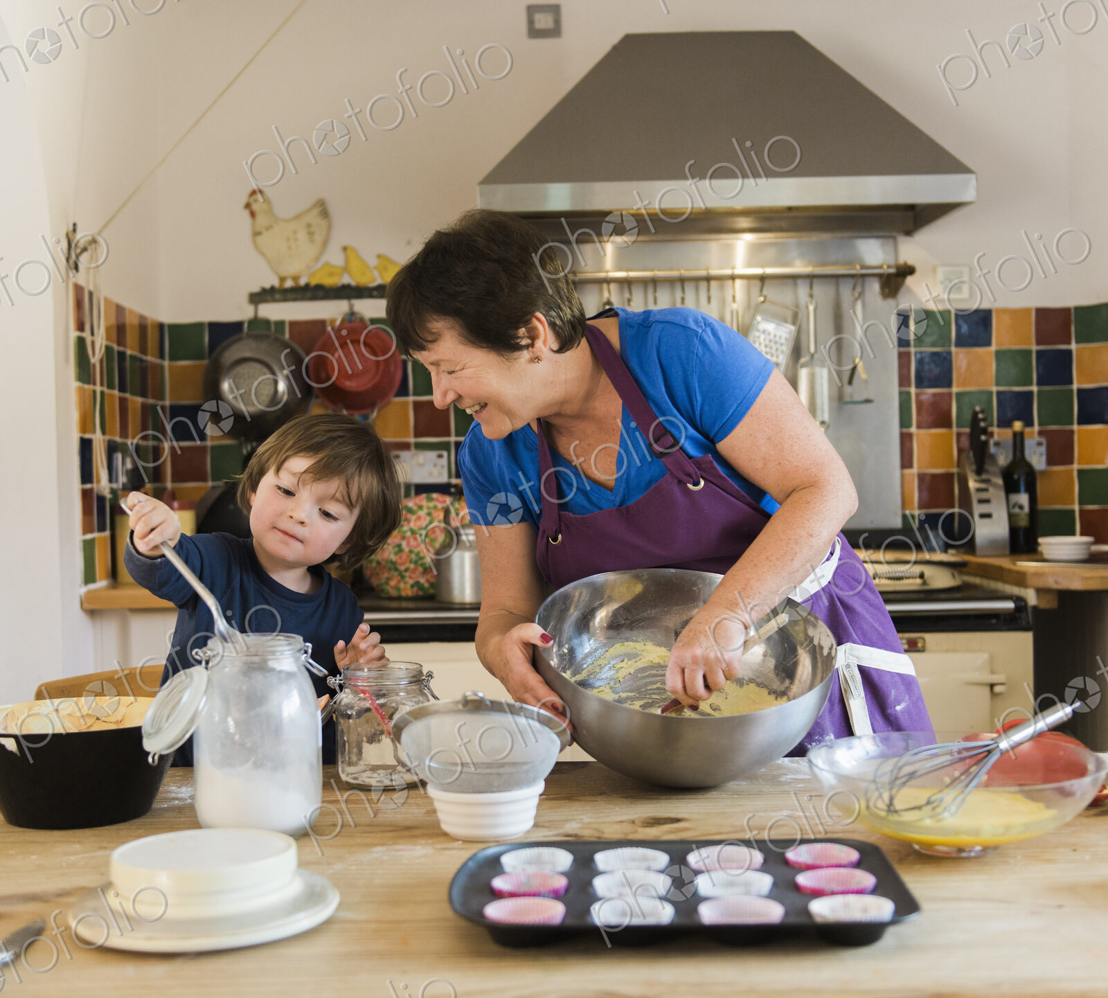 A woman and a child cooking at a kitchen table, making fairy cakes.
