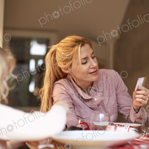 A woman and a child seated at a kitchen table sharing a cracker joke. A woman and a child seated at a kitchen table sharing a cracker joke.