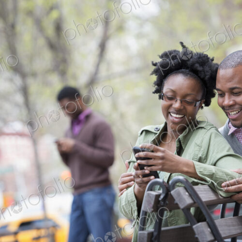 A woman and a man on a bench checking her phone. A woman and a man on a bench checking her phone.