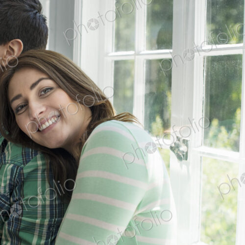A woman and a man standing close together, her head on his shoulder, smiling. A woman and a man standing close together, her head on his shoulder, smiling.