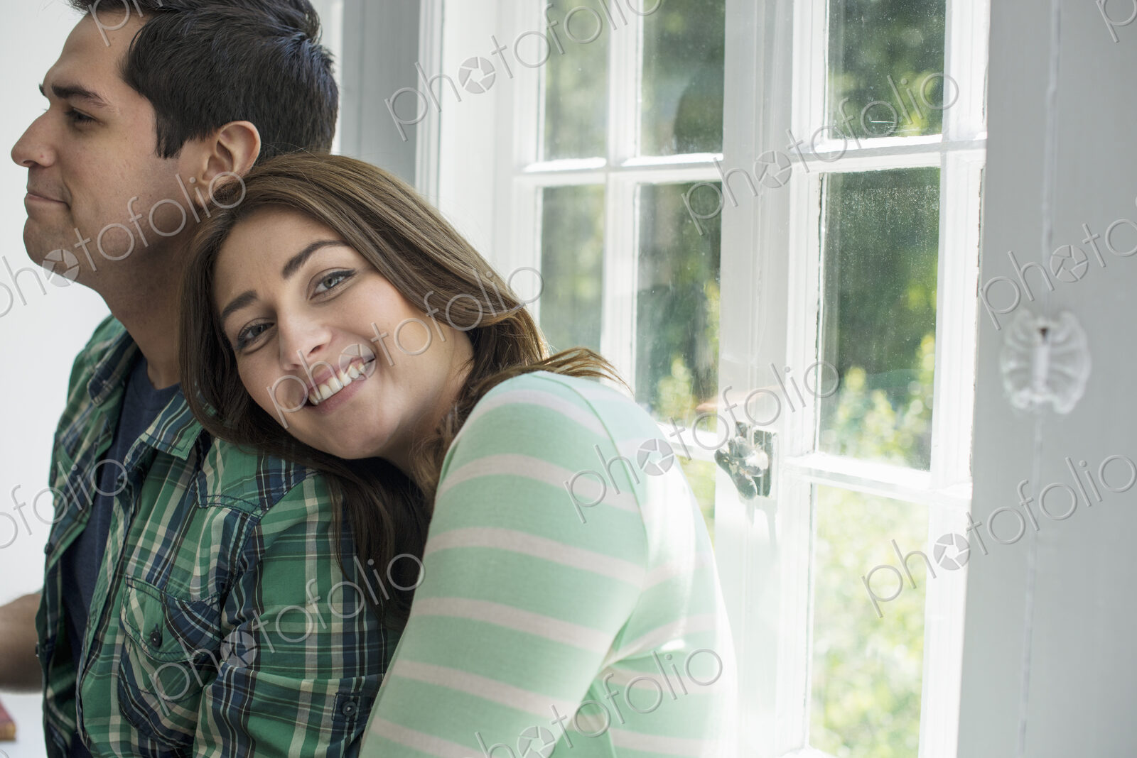 A woman and a man standing close together, her head on his shoulder, smiling.