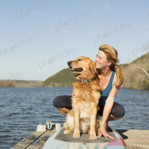 A woman and a retriever dog on a paddleboard on the jetty. A woman and a retriever dog on a paddleboard on the jetty.
