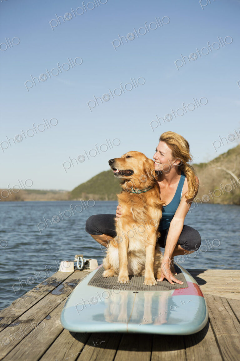 A woman and a retriever dog on a paddleboard on the jetty.