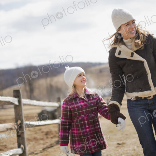 A woman and child walking along a path hand in hand on a farm in spring weather. A woman and child walking along a path hand in hand on a farm in spring weather.