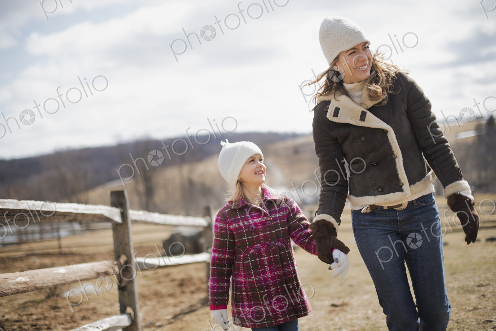 A woman and child walking along a path hand in hand on a farm in spring weather.