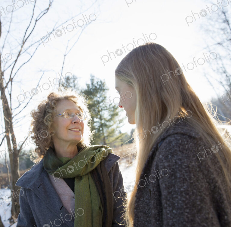 A woman and her adult daughter outdoors in winter snow.