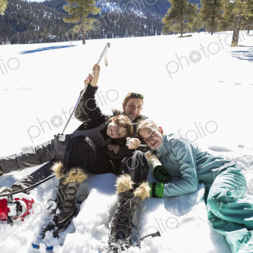 A woman and her two children lying in the snow in snow shoes and ski gear. A woman and her two children lying in the snow in snow shoes and ski gear.