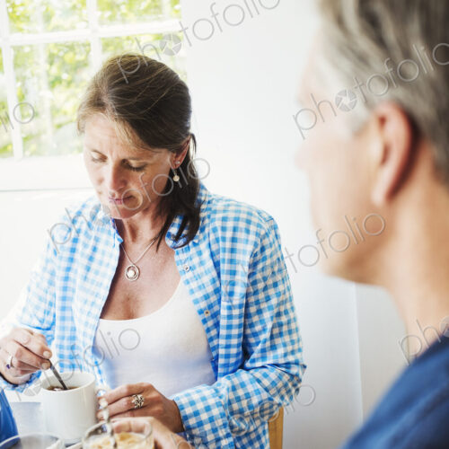 A woman and making talking over a cup of tea.