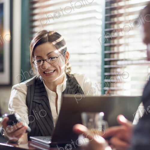 A woman and man seated at desks, working. Both using smart phones.