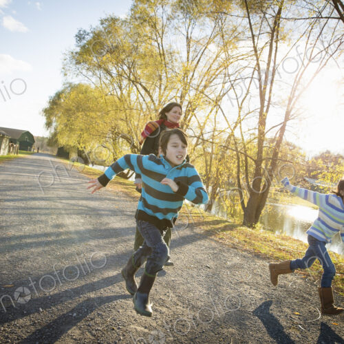 A woman and two children running by a lake, at an animal sanctuary. Autumn.