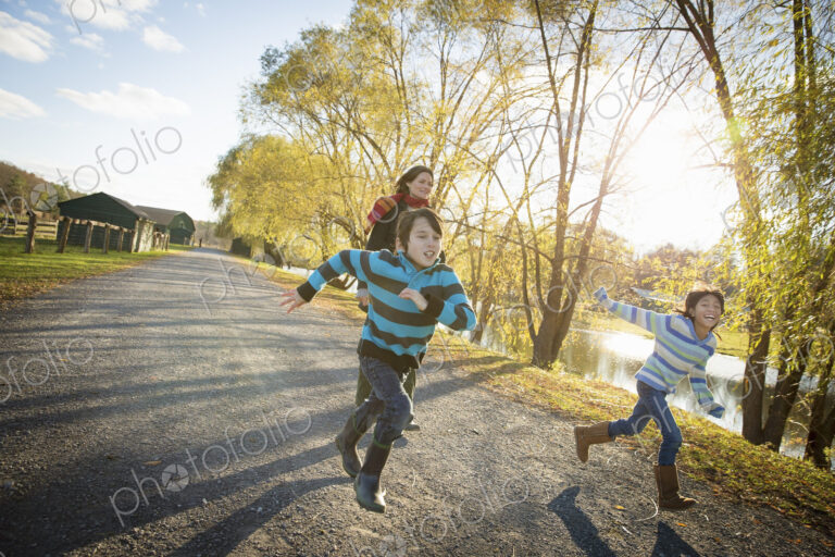 A woman and two children running by a lake, at an animal sanctuary. Autumn.