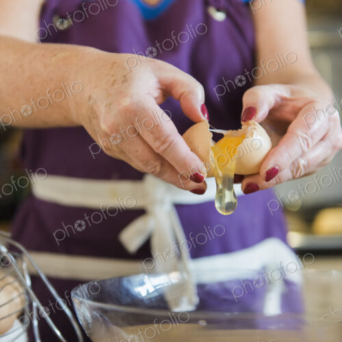 A woman at a kitchen table baking fairy cakes.