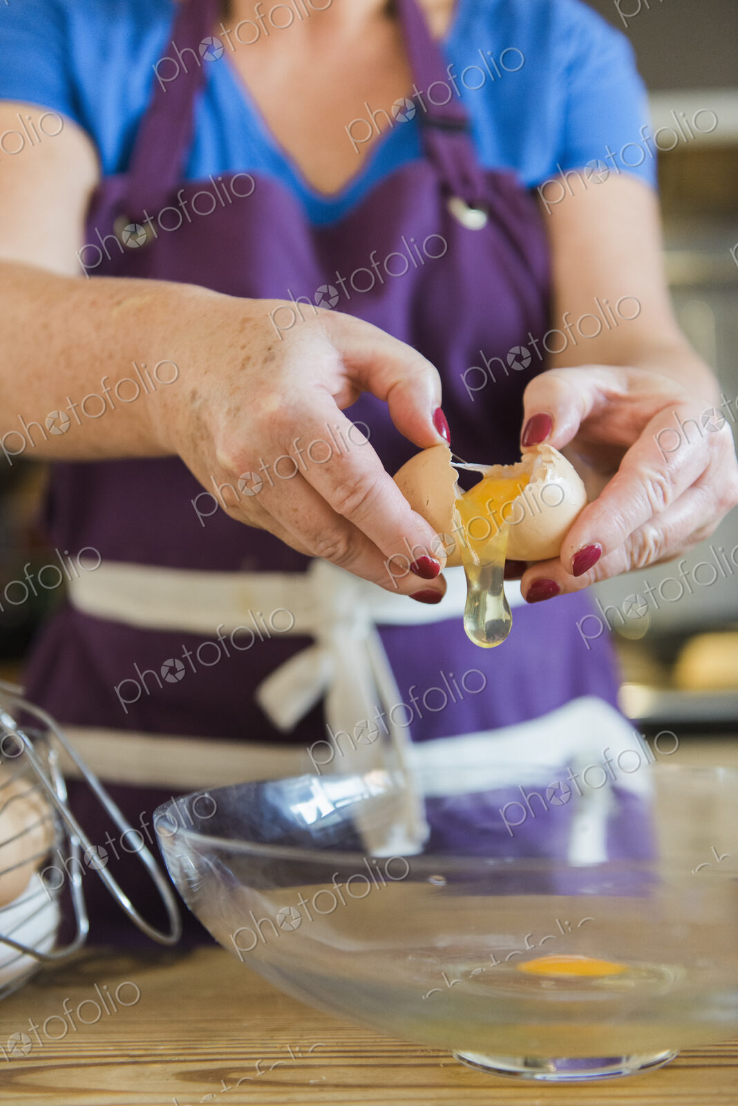 A woman at a kitchen table baking fairy cakes.
