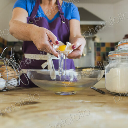 A woman at a kitchen table baking fairy cakes.