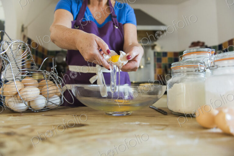 A woman at a kitchen table baking fairy cakes.