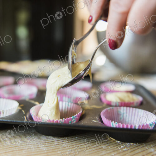A woman at a kitchen table baking fairy cakes. A woman at a kitchen table baking fairy cakes.