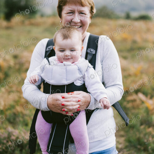 A woman carrying a baby in a baby carrier, on an autumn walk.
