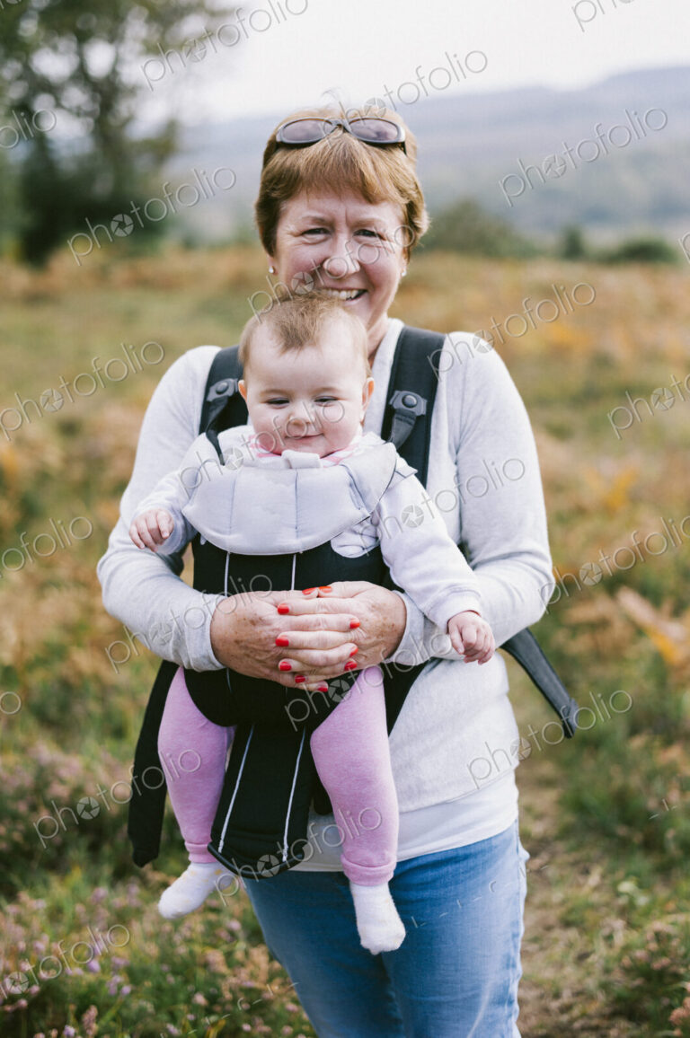 A woman carrying a baby in a baby carrier, on an autumn walk.