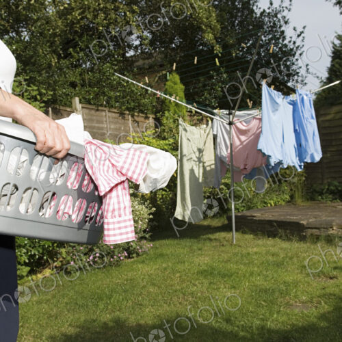 A woman carrying a basket of washing out to the washing line.