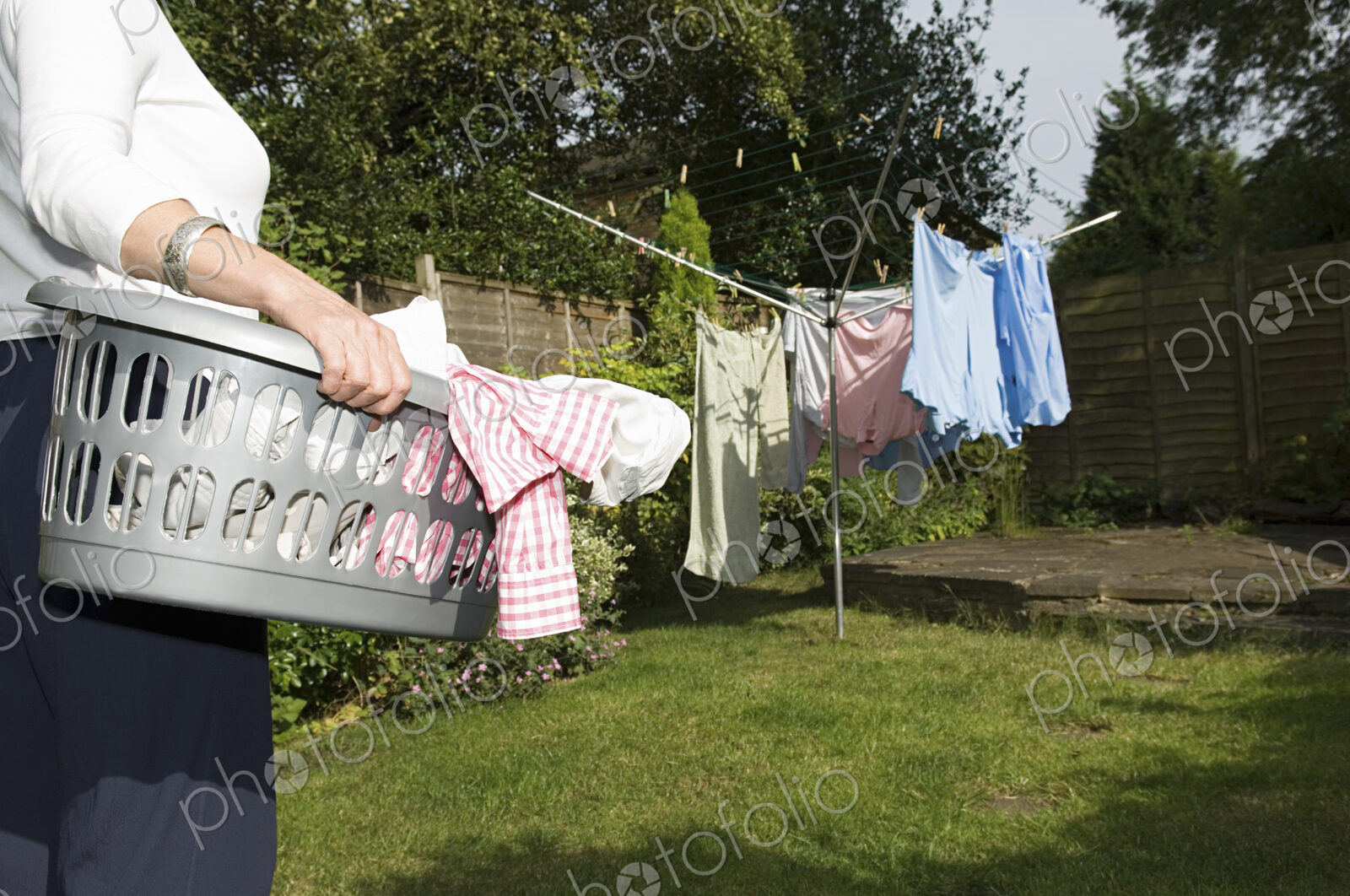 A woman carrying a basket of washing out to the washing line.