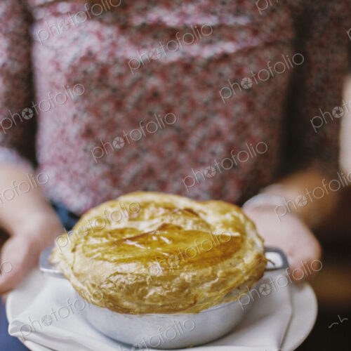 A woman carrying a fresh baked pastry topped pie on a plate. A woman carrying a fresh baked pastry topped pie on a plate.