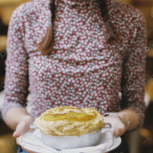 A woman carrying a fresh baked pastry topped pie on a plate. A woman carrying a fresh baked pastry topped pie on a plate.