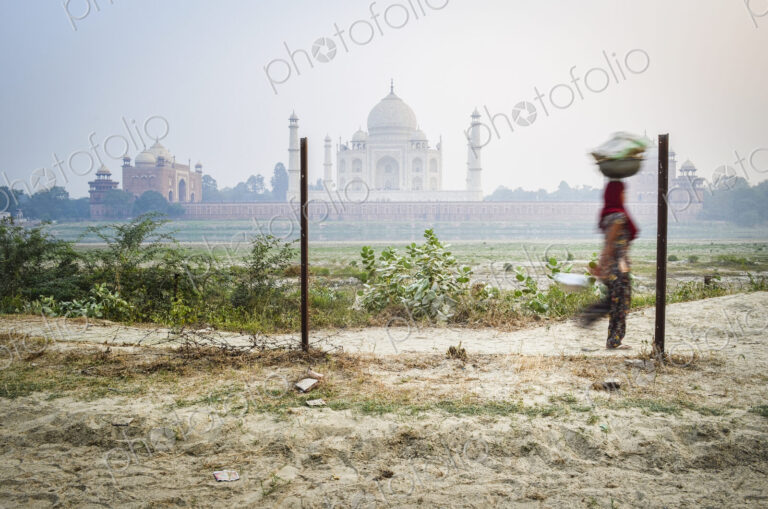 A woman carrying a load on her head, Taj Mahal in background