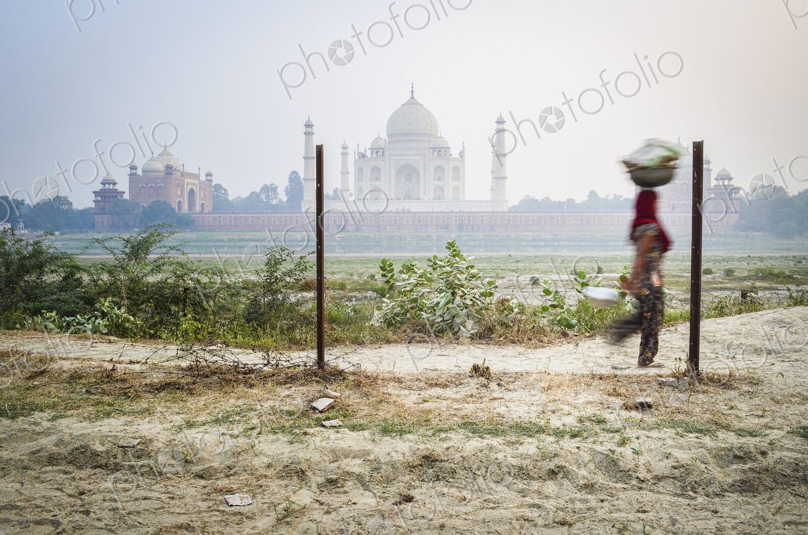A woman carrying a load on her head, Taj Mahal in background