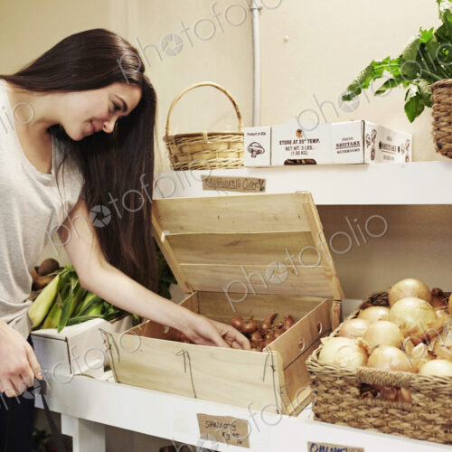 A woman choosing vegetables from a display at a farm shop.
