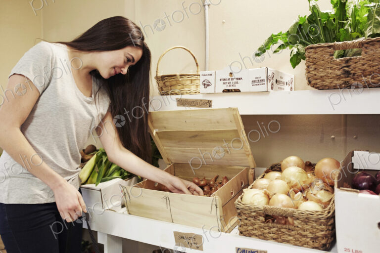A woman choosing vegetables from a display at a farm shop.